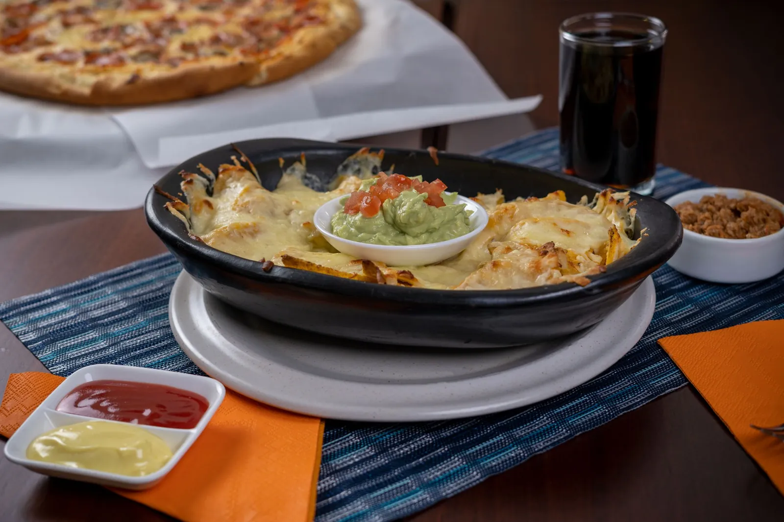 Mesa servida con nachos gratinados y pizza en Moka