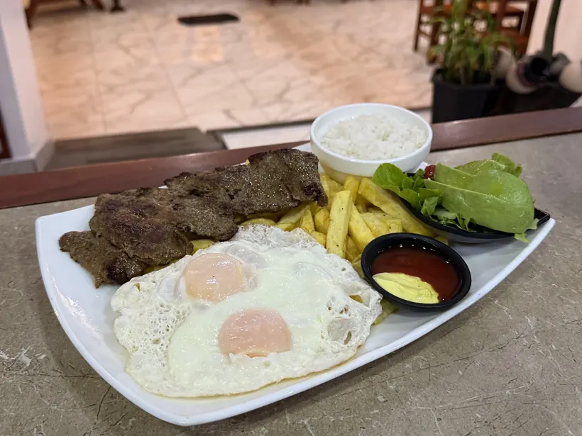 Churrasco con dos huevos, papas, arroz y ensalada